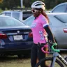 Female cyclist in pink shirt and helmet beside her bicycle