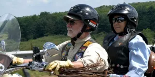 Two individuals on a motorcycle wearing helmets and jackets