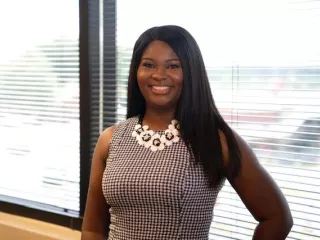  A woman in a dress standing in front of an office window